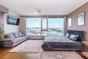 een slaapkamer met een bed en een bank en een groot raam bij Revalia Fahle Airport Bus-Station Studio in Tallinn