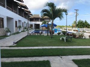a resort yard with a pool and a palm tree at Chalé na praia de Carapibus in Conde