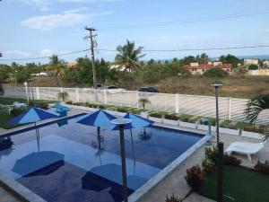 a swimming pool with blue umbrellas in a yard at Chalé na praia de Carapibus in Conde