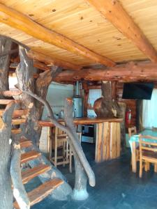 a log cabin with a table and chairs under a ceiling at CABAÑAS EL PALENQUE in Esquel