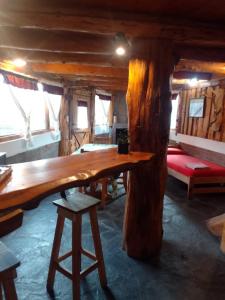 uma grande mesa de madeira num quarto de madeira com um banco em CABAÑAS EL PALENQUE em Esquel