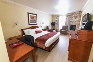 a hotel room with a bed and a television at Auberge l'Ambassadeur in Amqui