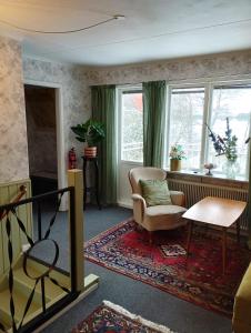 een woonkamer met een stoel, een tafel en ramen bij Som hemma in Grästorp