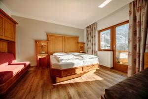 ein Schlafzimmer mit einem großen Bett und einem Fenster in der Unterkunft Hotel Lerch in St. Johann im Pongau