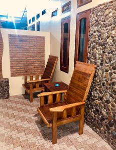 duas cadeiras de madeira sentadas ao lado de uma parede de pedra em R5 Keramba Inn em Bukit Lawang
