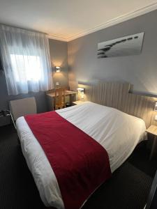 a hotel room with a large bed with a red blanket at initial by balladins Amiens / Longueau in Longueau