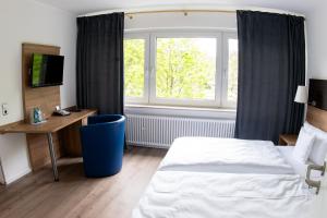 a bedroom with a bed and a desk and a window at Kaisergarten Hotel I Restaurant in Neuenrade