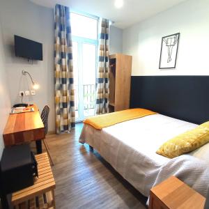 1 dormitorio con cama, escritorio y ventana en H33 Hôtel, en Niza