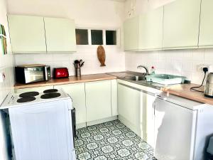 a white kitchen with a sink and a dishwasher at The Captains Lookout-Sleeps 6! in St. Leonards