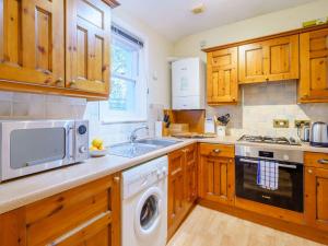 a kitchen with wooden cabinets and a sink and a dishwasher at 2 Bed in Keswick 86100 in Keswick