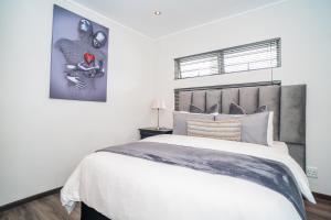 a white bedroom with a large bed and a picture at The Escalante in Johannesburg
