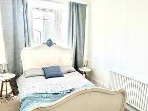 a white bed with blue pillows in a bedroom at The Captains Lookout-Sleeps 6! in St. Leonards