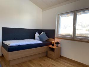 een slaapkamer met een bed met een blauwe deken en een raam bij Geißhof in Rettenberg