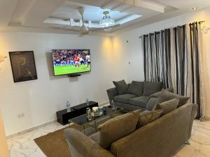 a living room with a couch and a tv on the wall at The Retreat Apartments in Brusubi