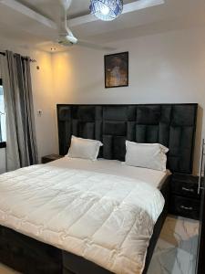 a bedroom with a large bed with a black headboard at The Retreat Apartments in Brusubi