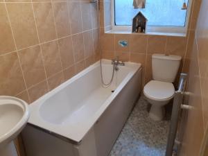 a bathroom with a toilet and a tub and a sink at Single Room in Oldham