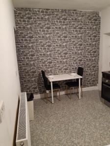 a room with a table and two chairs and a brick wall at Single Room in Oldham