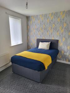 Larchmont House في ليستر: غرفة نوم بسرير وبطانية صفراء وزرقاء