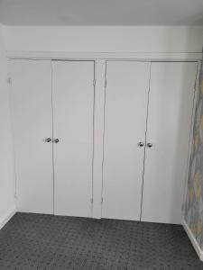 two white cabinets in a room with a wall at Larchmont House in Leicester