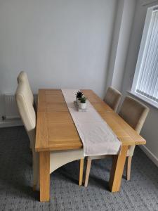 Larchmont House في ليستر: طاولة طعام خشبية مع كراسي ومفرش
