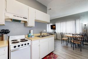 a kitchen with white cabinets and a sink and a table at Okaloosa Island Studio in Fort Walton Beach