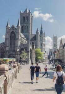un grupo de personas caminando por una calle frente a una catedral en The Old One Fifteen by Romy&Travis en Ghent