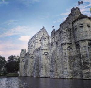 un château dans l'eau avec des drapeaux sur lui dans l'établissement The Old One Fifteen by Romy&Travis, à Gand
