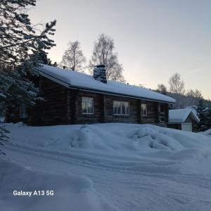 une cabane en rondins avec un tas de neige devant elle dans l'établissement A room (or 2 or 3) in a Lapland House of Dreams, à Rovaniemi