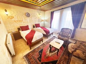 a bedroom with two beds and a chair and a table at Balloon Cave Hotel in Goreme