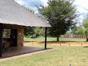 Cabaña de madera con porche y techo de hierba en Moletani Game Ranch, en Kareefontein