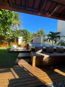 a patio with a couch on a wooden deck at Casa com Piscina in Canavieiras