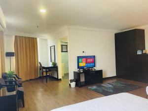 een woonkamer met een televisie en een bed bij Remington Hotel in Muar
