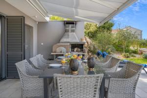 a patio with a table and chairs with a fireplace at Villa Tyra in Ražanj