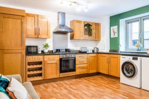 a kitchen with wooden cabinets and a washer and dryer at Emerald Retreat - City Centre - Free Parking, Fast WiFi and Smart TV by Yoko Property in Derby
