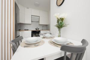een witte keuken met een witte tafel en stoelen bij Elegant Apartment in the centre of Gdynia by Renters in Gdynia