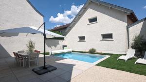 une terrasse avec une table, un parasol et une piscine dans l'établissement La Maison de Caro, à Gevrey-Chambertin