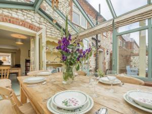 a wooden table with a vase of purple flowers on it at 3 Bed in Thornham KT111 in Thornham