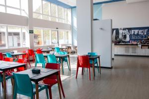 a dining room with tables and colorful chairs at ibis budget Muriae in Muriaé