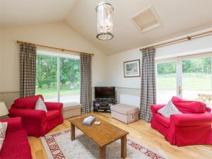 sala de estar con 2 sillas rojas y TV en 3 Bed in Achnacarry CA018 
