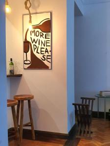 una pared con una foto de una botella de vino y dos taburetes en Apartamento 4 quartos 500m Arpoador, en Río de Janeiro