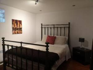 een slaapkamer met een zwart bed met kussens erop bij Comfortable 2-bedroom, private kitchen and bathroom in Montreal