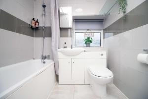 a bathroom with a toilet and a sink and a tub at Alma Cottage by StayStaycations in Rhondda