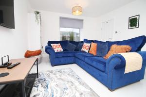 a blue couch in a living room with a table at Alma Cottage by StayStaycations in Rhondda