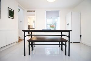 a dining table with a bench in a room at Alma Cottage by StayStaycations in Rhondda