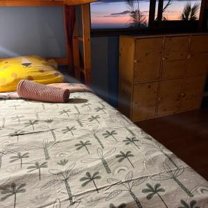 een slaapkamer met een bed met een deken met palmbomen erop bij Dodo House auberge de jeunesse in Saint-Leu