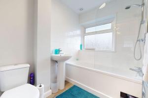 a white bathroom with a tub and a sink and a toilet at CONeN Dagenham Home in Goodmayes