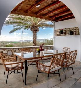 a table and chairs on a patio with a palm tree at Noho Villas @ Sunlit house Paros in Nea Cryssi Akti