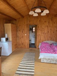 a room with a bed in a wooden room with a kitchen at Nádas fogadó és panzió in Teresztenye