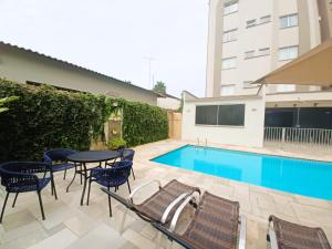 a patio with a table and chairs next to a pool at Hotel Riviera in Araçatuba
