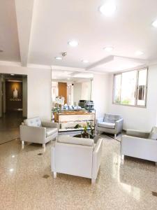 a living room with white couches and chairs at Hotel Riviera in Araçatuba